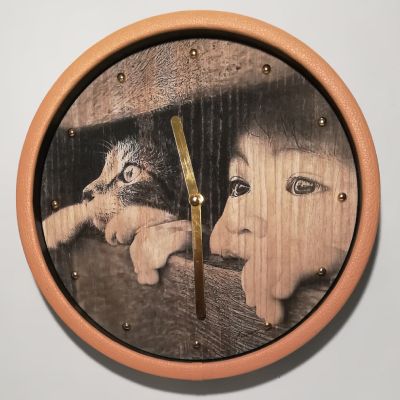 Orologio da parete o tavolo in quercia con immagine di bimbo e gatto curiosi. Cornice kaki, dettagli dorati: un attimo magico che unisce infanzia, natura e design raffinato.