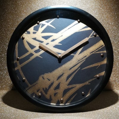 Elegante orologio da parete nero con canne di bambù dorate, sintesi di modernità e natura. Un'opera d'arte funzionale che aggiunge calore e raffinatezza a qualsiasi ambiente contemporaneo. Il design organico e dinamico crea un punto focale sofisticato, unendo stile minimalista ed elementi naturali con un tocco di eleganza.