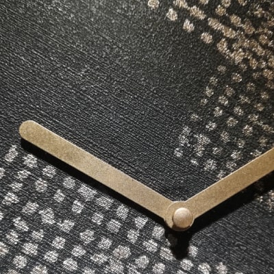 Secondo particolare: Un orologio da parete nero con puntini e lancette dorati. Un design geometrico e raffinato che trasmette modernità e lusso. Un’aggiunta sofisticata e contemporanea all’arredamento.