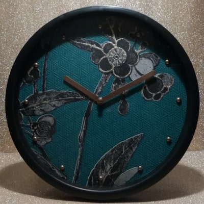 Esplora l'eleganza della natura con questo orologio da parete verde, impreziosito da una lavorazione a rombi e decorazioni floreali in nero, argento e oro. Lancette dorate su fondo verde, cornice nera: un equilibrio perfetto tra modernità e raffinatezza, trasformando l'orologio in un'opera d'arte unica.