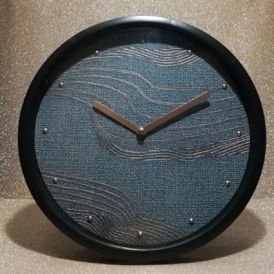 L'orologio blu moderno con onde dorate dall'effetto tessuto unisce modernità e lusso. La base tessile blu, le onde dorate e le lancette nere creano un design sofisticato. Un regalo unico per aggiungere stile e dinamismo all'arredamento.
